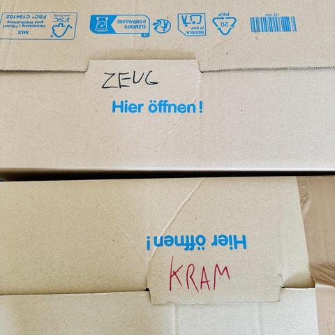 Zwei Umzugskartons von oben. Auf dem einen steht das Wort Zeug, auf dem anderen das Wort Kram.
