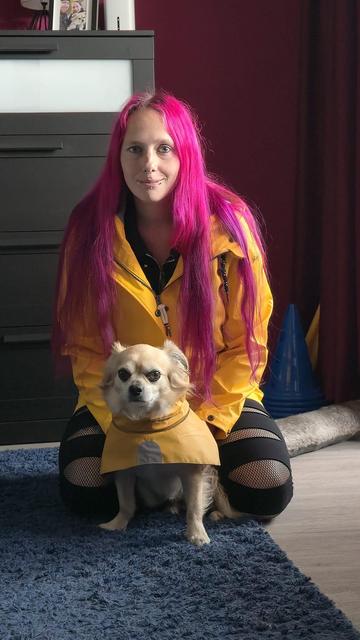 Frau (ich) mit pinken Haaren trägt einen quietschgelben Regenmantel.
Sie kniet auf dem Boden und vor ihr sitzt ein kleiner blonder Hund und trägt ebenfalls einen quietschgelben Regenmantel.