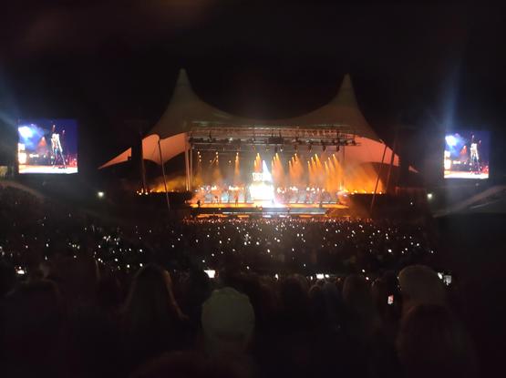 Schnappschuss aus dem Zuschauerbereich auf die Waldbühne in Berlin mit den zwei großen Screens an jeder Seite. Die Hauptbühne und die zwei   Kuppeln getaucht in oranges Bühnenlicht. Gianna Nannini Konzert.