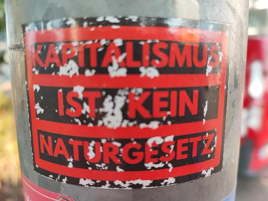 Laternenpfahl 

Aufkleber 
schwarzer Hintergrund 
rote Schrift 

Kapitalismus 
ist kein
naturgesetz