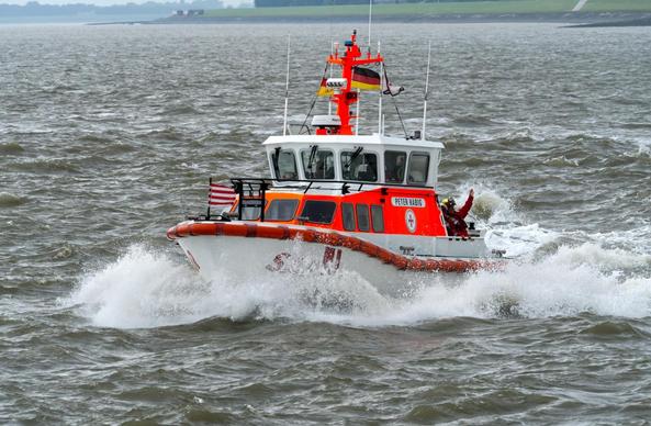 Foto, Rettungsboot Peter Habig in Fahrt bei Wind und Welle vor Wilhelmshaven. Das Wetter ist trüb und grau. Im Hintergrund ist der Deich zu sehen.